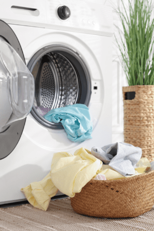 Fresh laundry basket beside open front-load washing machine in clean modern laundry room.