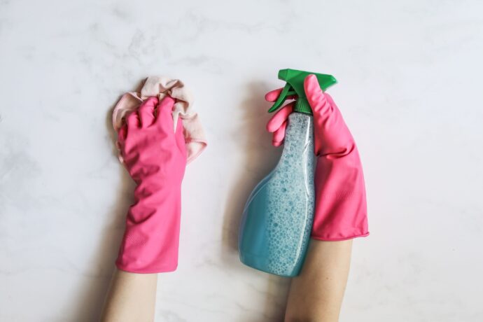 Gloved hands cleaning a surface with a spray bottle
