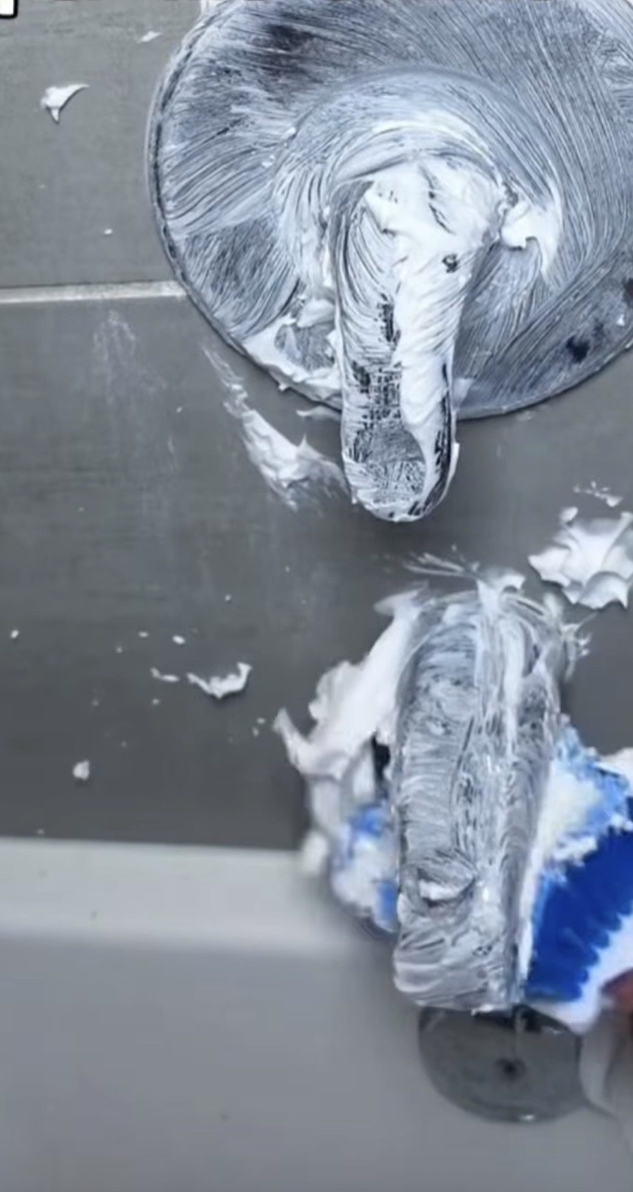 Cleaning paste spread over a shower faucet and tub spout with a brush