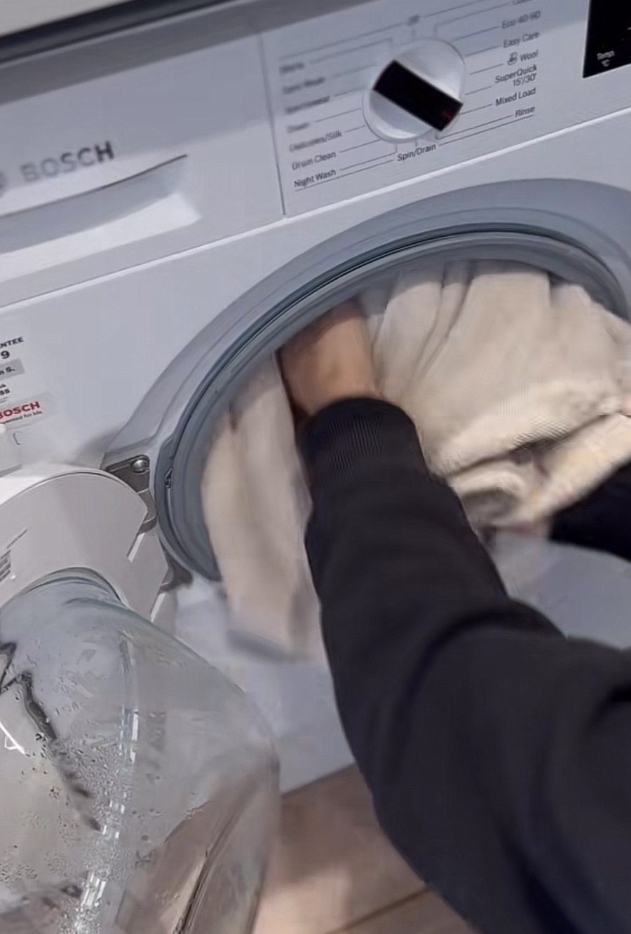 Pouring white vinegar into the washing machine drum with towels to keep them soft